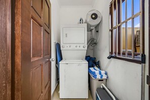Une buanderie équipée d’un lave-linge, d’un sèche-linge et d’une fenêtre donnant sur un paysage agréable.