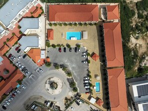 An aerial view of a hotel with multiple swimming pools, a parking lot, and a central circular area. - 2BR Condo w/ Pool & Balcony, 1 Min to Eagle Beach (Noord)
