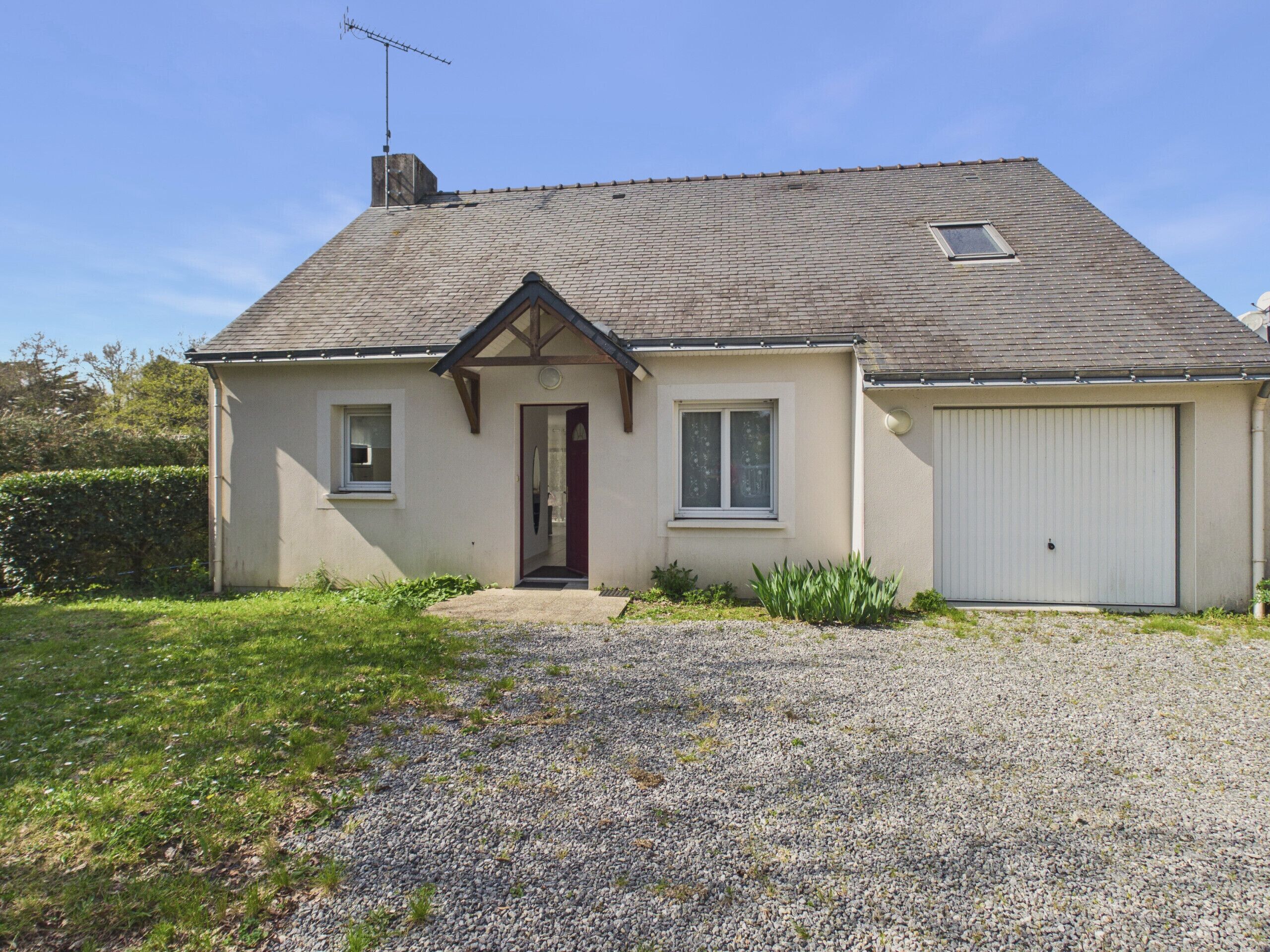 Ein zweistöckiges Haus mit Eingangstür, Garage und Auffahrt mit Kies.