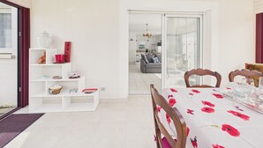 En spiseplads med et bord dækket til fire personer, et lyst indre og udsigt til stuen.