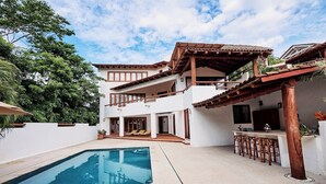 Ein zweistöckiges Haus mit Swimmingpool, Außenbereich zum Sitzen und einer Bar.