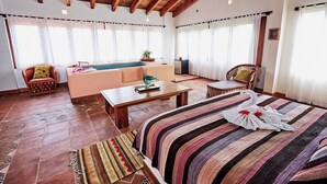 Ein geräumiges Zimmer mit einem großen Bett, einem Sofa, einem kleinen Tisch und einem Poolbereich.