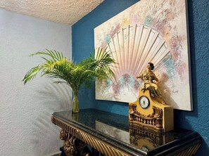 Eine dekorative Uhr mit einer goldenen Figur darauf, auf einem Marmortisch vor einer blauen Wand platziert.