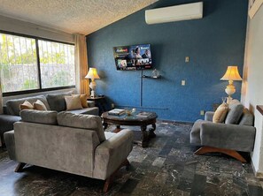 A living room with a sofa set, a coffee table, and a TV mounted on the wall. - La Quinta de Don Hugo (Ixtapa)