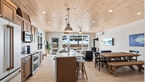 Una cocina moderna con armarios de madera, una isla central y una zona de comedor con mesa y sillas de madera.