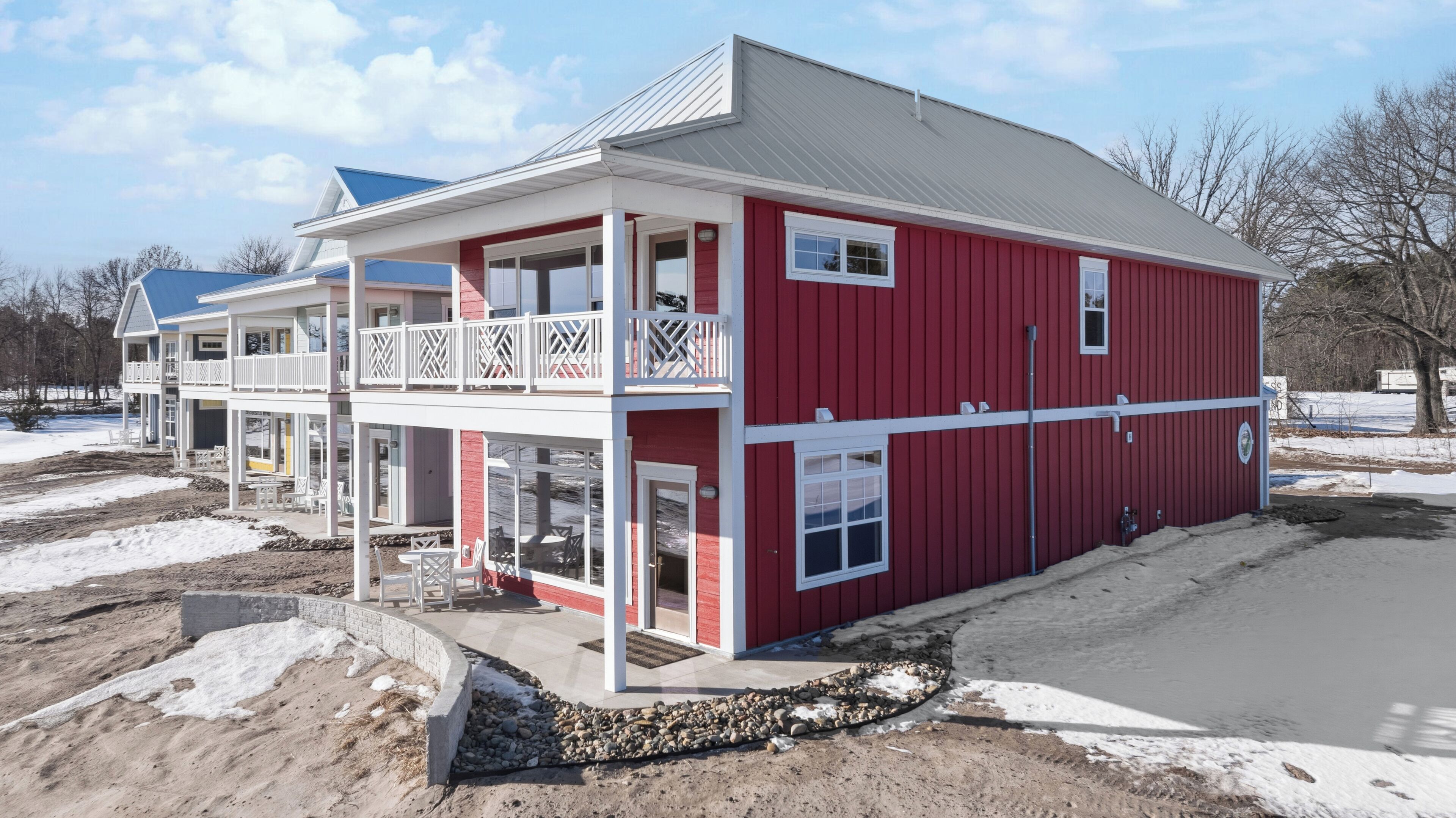 A two-story building with a red exterior, balconies, and a covered outdoor seating area.