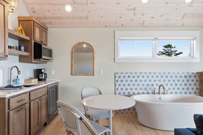 A kitchen with wooden cabinets, a microwave, a coffee maker, and a dining area with wicker chairs.