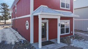 A red building with a white door and a small porch.
