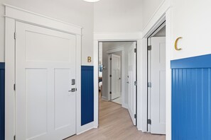 A hallway with white doors, blue trim, and a letter 'B' on one door. - Modern Mille Lacs Suite | Sleeps 6 (Garrison)