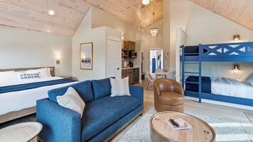Une pièce comprenant un lit, un canapé bleu, un fauteuil en cuir marron, une table à manger et un lit superposé.