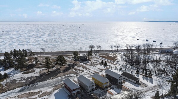 A residential area with houses, a road, and a frozen lake.