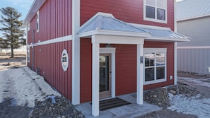 A red building with a white door and a small porch.