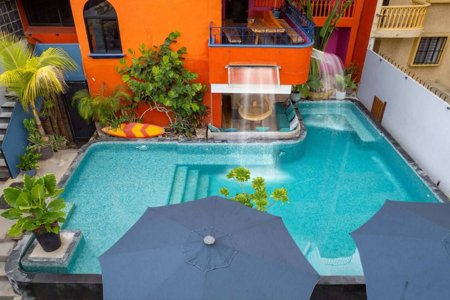 Ein Schwimmbecken mit Whirlpool, umgeben von Kübelpflanzen und Sonnenschirmen.