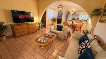 A living room with a TV, sofa, coffee table, and dining area.