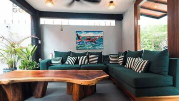 Uma sala de estar moderna com um sofá seccional, uma mesa de centro de madeira e um quadro de flamingo na parede.