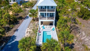 A multi-story beachfront property with a pool, balconies, and a road leading to the entrance. - Sand Casas (Port St. Joe)