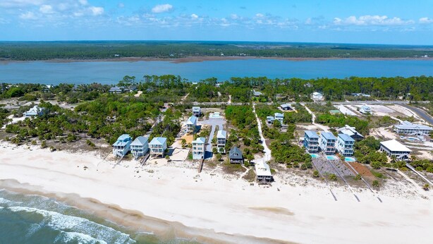 An aerial view of a coastal area with beachfront properties, a sandy beach, and a body of water. - Sand Casas (Port St. Joe)