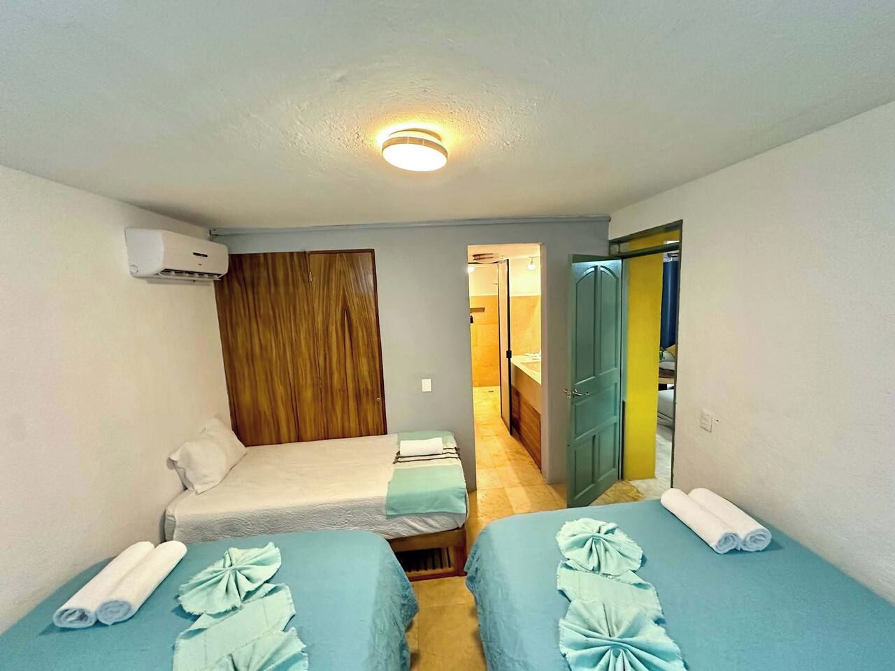 Een kamer met twee bedden, een houten garderobe en een badkamer die door een open deur zichtbaar is.