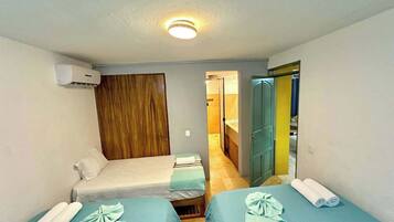 Een kamer met twee bedden, een houten garderobe en een badkamer die door een open deur zichtbaar is.