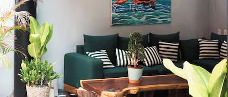 Un sofá verde con almohadones a rayas, una mesa de centro de madera y una planta en maceta.