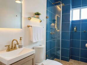 A modern bathroom with a glass-enclosed shower, a white sink with gold fixtures, and a mirror above the vanity. - Minimalism Apartment at Ixtapa Zihuatanejo (Ixtapa Zihuatanejo)
