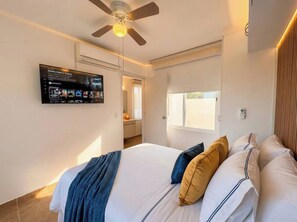 A bedroom with a bed, pillows, a ceiling fan, and a wall-mounted TV displaying a Netflix interface. - Minimalism Apartment at Ixtapa Zihuatanejo (Ixtapa Zihuatanejo)