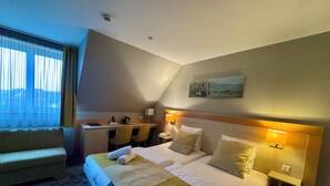 A hotel room with a bed, a desk, a chair, a lamp, and a painting on the wall. - Logis Hôtel Restaurant & Spa Au Soleil (Wettolsheim)
