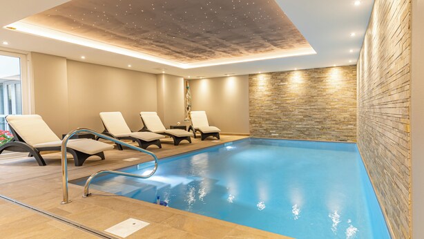 A swimming pool with lounge chairs and a stone wall. - Logis Hôtel Restaurant & Spa Au Soleil (Wettolsheim)
