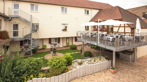 A two-story building with a balcony, outdoor seating, and a garden area. - Logis Hôtel Restaurant & Spa Au Soleil (Wettolsheim)