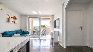 Un interno moderno con un divano bianco, un tavolo da pranzo e vista su un'area esterna.