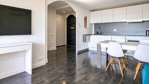 Una cucina moderna con mobili bianchi, un televisore a schermo piatto e un'area pranzo con sedie bianche.