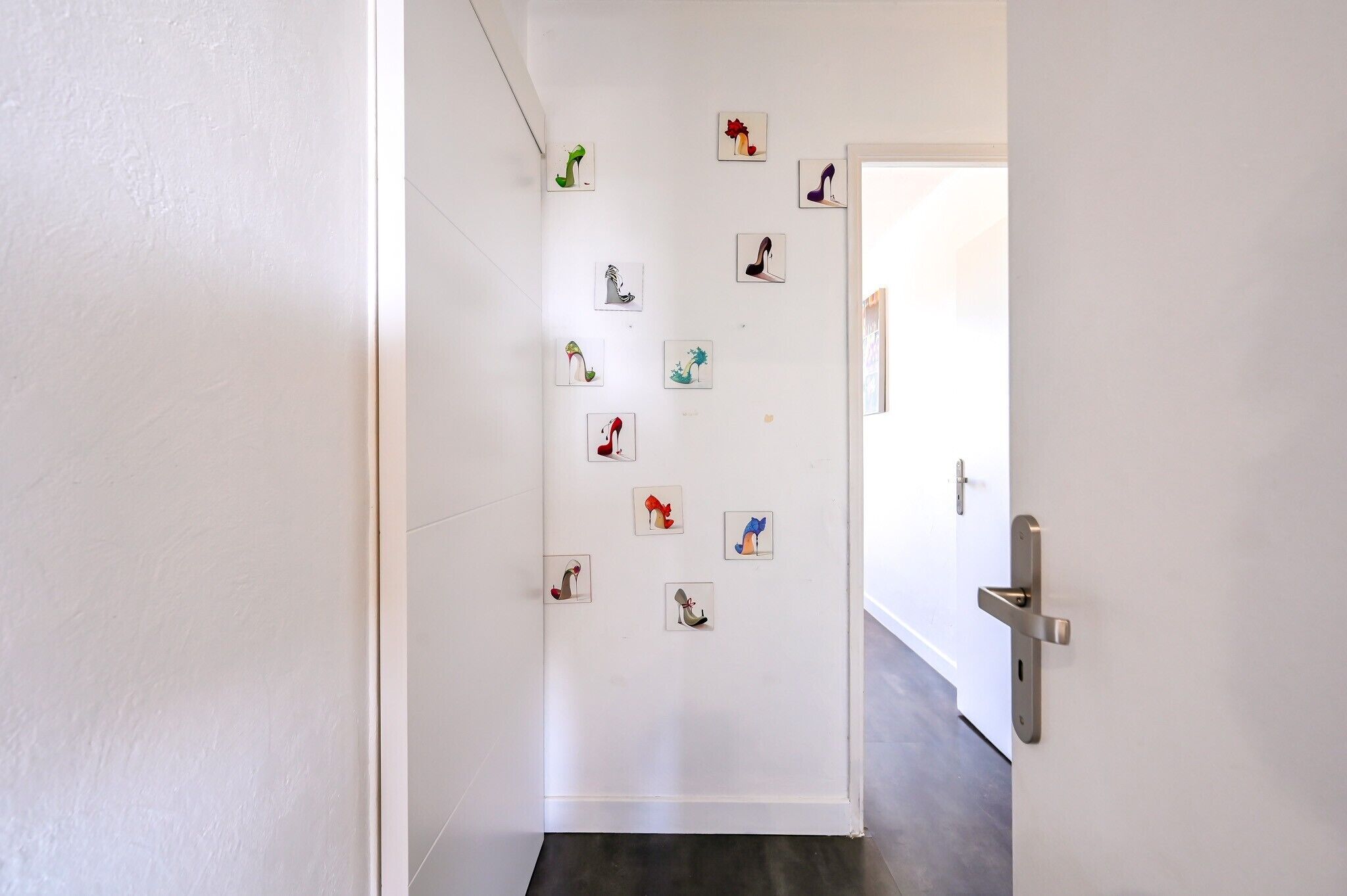 A hallway with a white wall and a door with a modern handle.