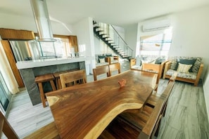 A modern kitchen with a central island, a staircase, and a seating area with a sofa and chairs.