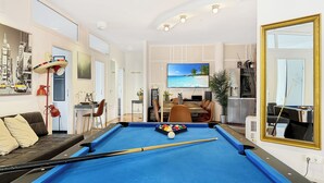 Ein Zimmer mit Billardtisch, einer Sitzecke, einem Essbereich und einem Fernseher.