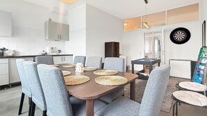 A modern dining area with a round table, grey upholstered chairs, and woven placemats.