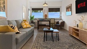 A living room with a sofa, coffee table, and a TV displaying 'NETFLIX'.