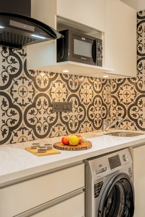 Una cocina equipada con microondas, horno y lavadora.