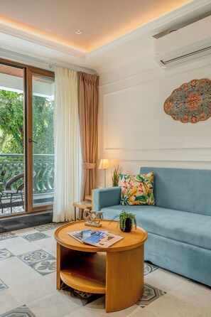 A room with a blue sofa, a round wooden coffee table, a potted plant, and a decorative wall piece.