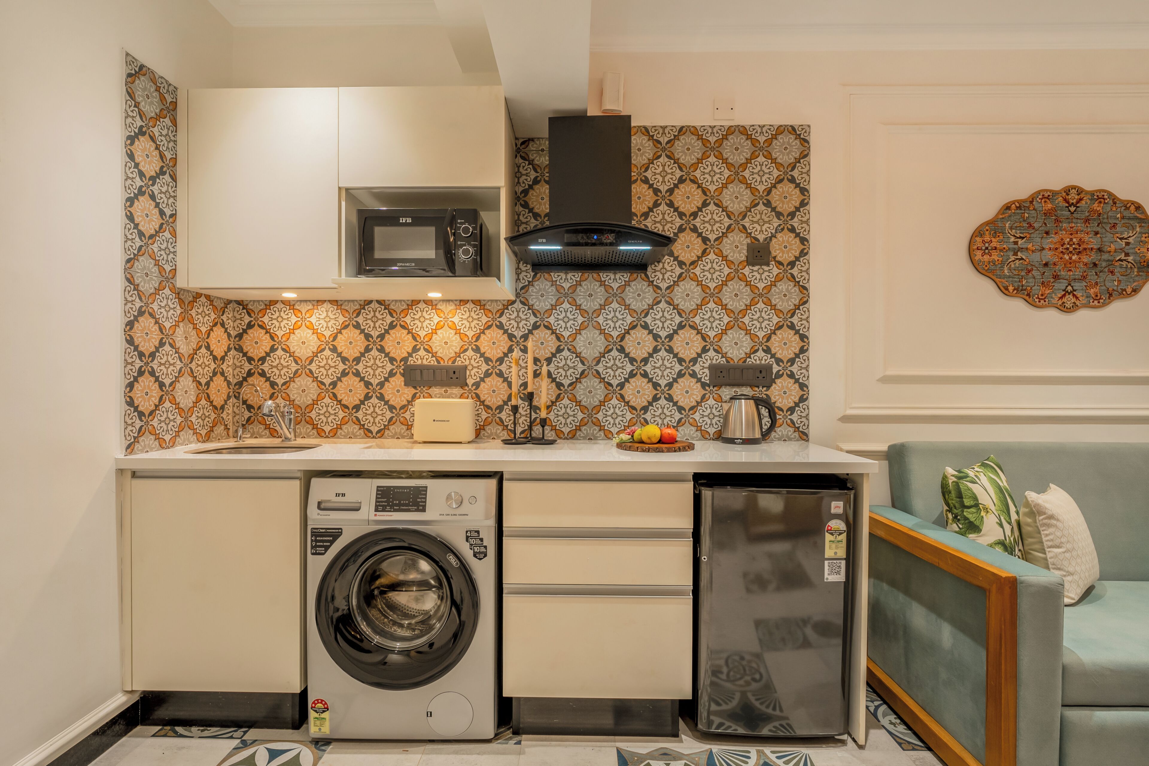 Une cuisine compacte équipée d’un lave-linge, d’un four à micro-ondes, d’une machine à café et d’un réfrigérateur.