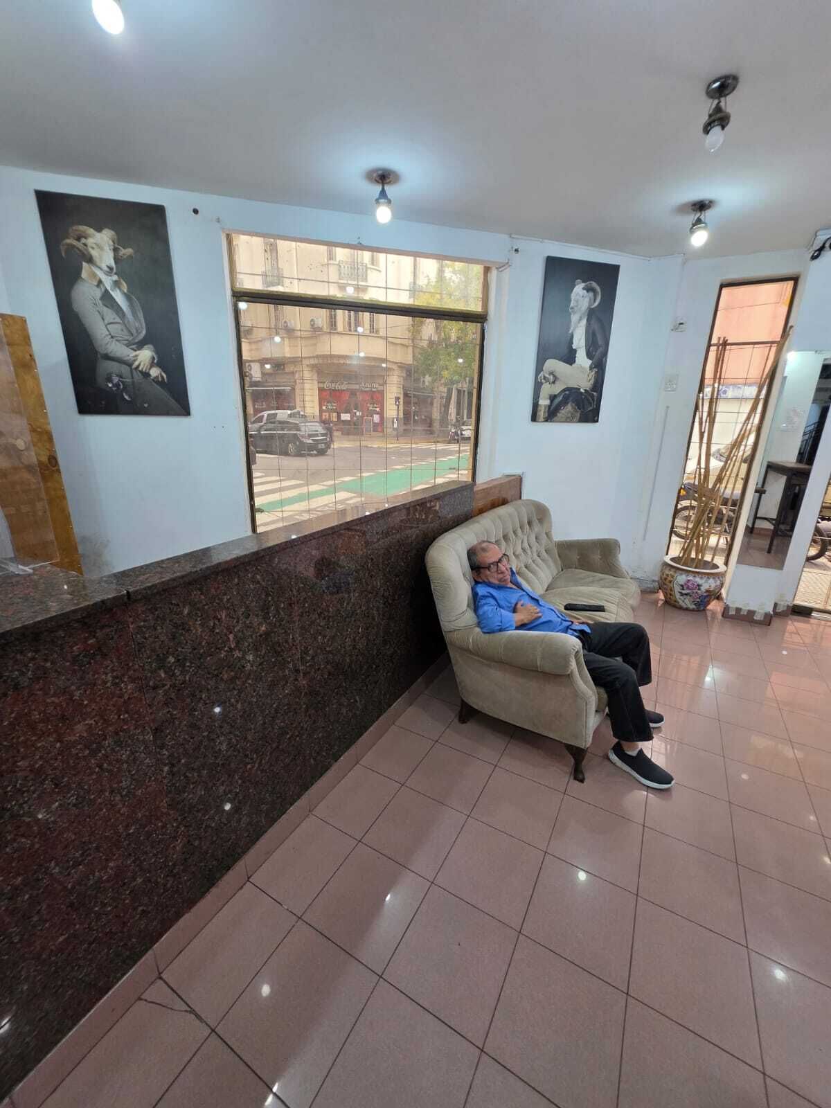 A waiting area with a marble reception desk, a sofa, and a window with a view of the street.