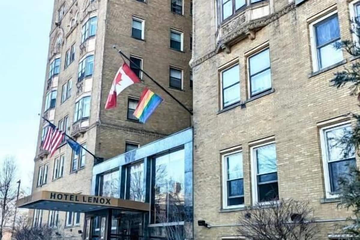 A hotel with a classic brick facade, a glass entrance, and flags.