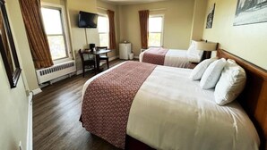 A hotel room with two beds, a desk, a television, and a window. - Lenox Hotel and Suites (Buffalo)