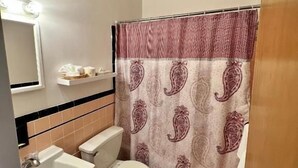 A bathroom with a toilet, sink, and shower curtain. - Lenox Hotel and Suites (Buffalo)