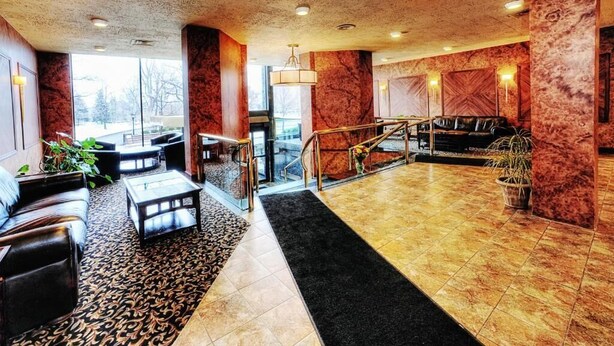 A lobby with a staircase, seating area, and a view of the outdoors. - Lenox Hotel and Suites (Buffalo)