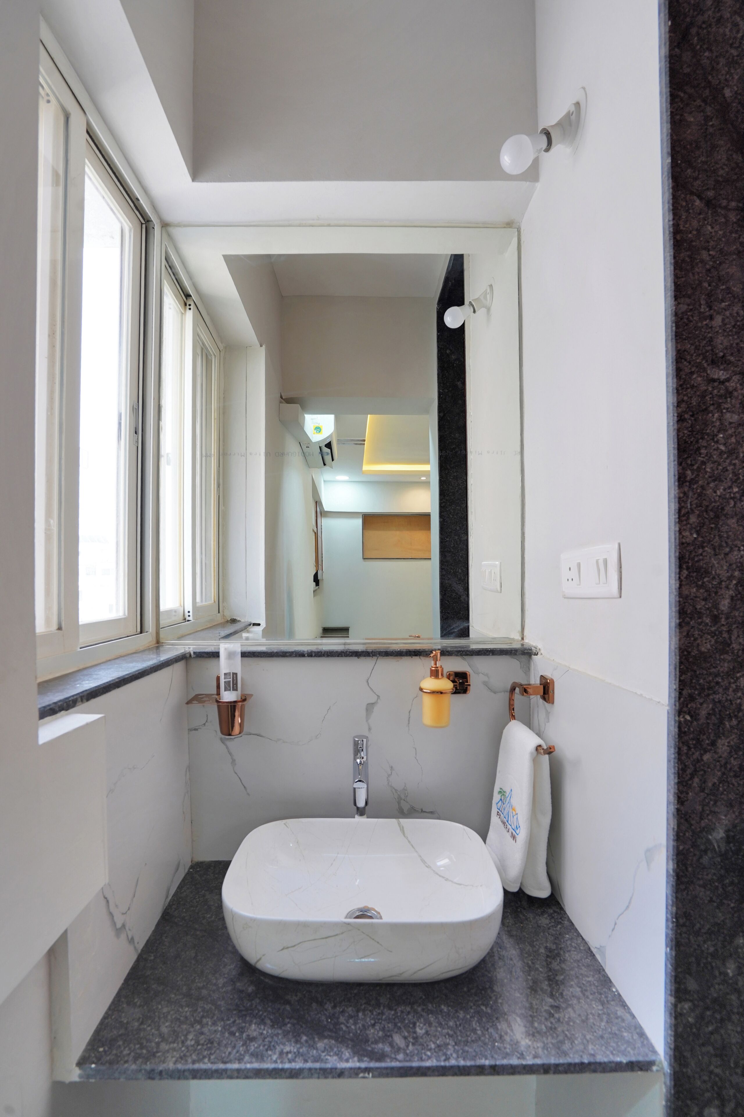 Un baño con un lavabo blanco, un espejo y una ventana.