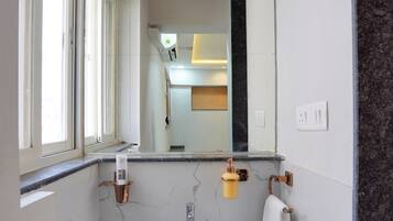 Un baño con un lavabo blanco, un espejo y una ventana.
