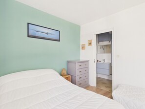 Une chambre à coucher avec un lit, une commode, un miroir et un tableau encadré accroché au mur.