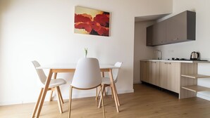 A modern kitchen with wooden cabinets, a white countertop, and a single chair.