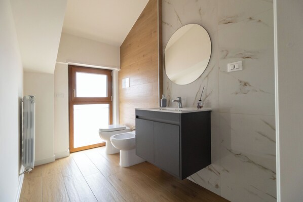 Une salle de bain moderne avec un meuble-lavabo en bois, un miroir rond et des toilettes.