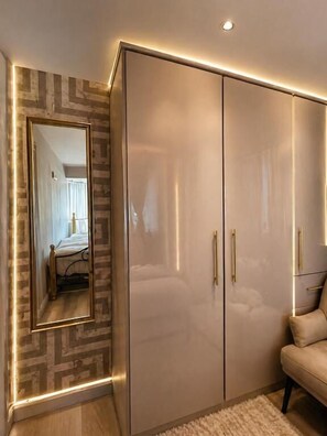 A bedroom with a large wardrobe, a mirror, and a bed.
